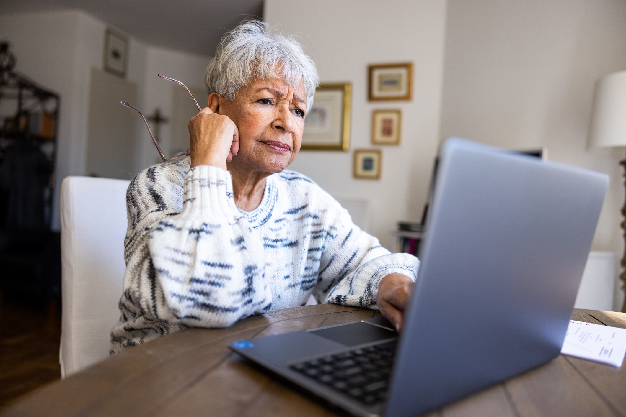 Older woman looking carefully at her laptop screen.
